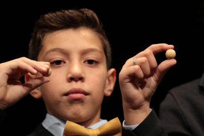 Un niño de Sant Ildefonso muestra un quinto premio de la lotería de Navidad, el 02308.