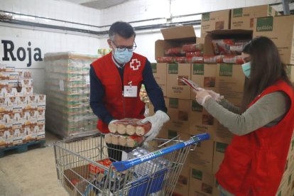 Dos voluntaris de Creu Roja Tarragona omplint el carro d'aliments per una persona en situació de vulnerabilitat.