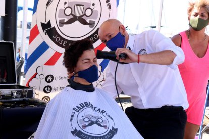 Un peluquero enjugando el cabello de una mujer que ha participado en la quinta edición de la campaña 'Déjate tomar el pelo' en Cambrils.