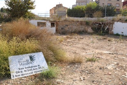 Solar y restos de escombros a raíz de|junto a río en l'Espluga de Francolí donde destaca el mensaje de los propietarios de una bodega destruida, comunicando la nueva ubicación.