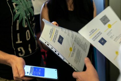 Un membre de la tripulació d'un vaixell comprova el certgificat digital COVID de la UE als passatgers que pugen.