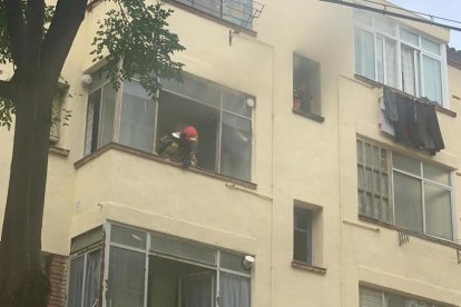 Un bombero saca la cabeza por una de las ventanas del piso.