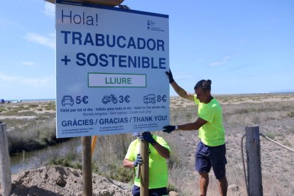 Operarios colocando los carteles que informan sobre la regulación del acceso a la barra del Trabucador.