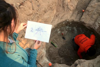 La doctora en Prehistoria, Georgina Prats, mostrando un dibujo del uso de uno de los silos descubiertos al yacimiento Mas Cap del Ferro, en Nulles.