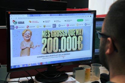 Pla obert amb una persona en escorç mirant una pantalla amb la web per comprar un bitllet de la Grossa de Cap d'Any.