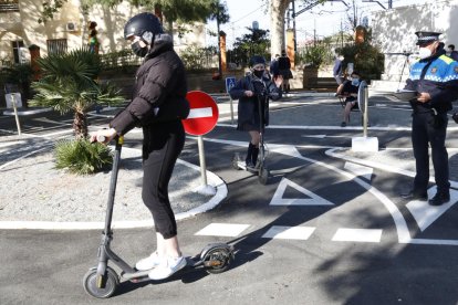 Unes noies fent pràctiques amb patinet elèctric en un circuit tancat a Reus, sota la supervisió d'un agent de la Guàrdia Urbana.