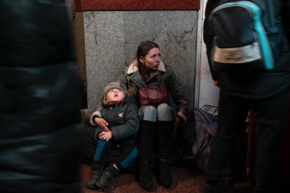 Una mujer y un niño se sientan en la estación de trenes de Lviv durante la invasión militar rusa en Ucrania.