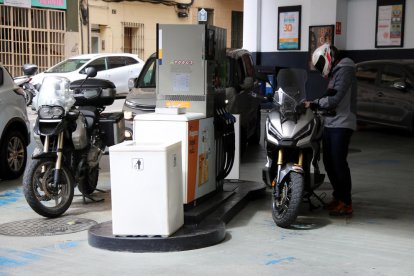 El conductor de una moto poniendo combustible en la gasolinera.