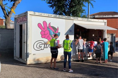 Dos agents de la Guàrdia Civil davant una caseta temporal de venda de petards on diversos clients fan cua.