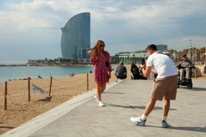 Dos turistes fent-se una foto amb l'hotel Vela de fons.