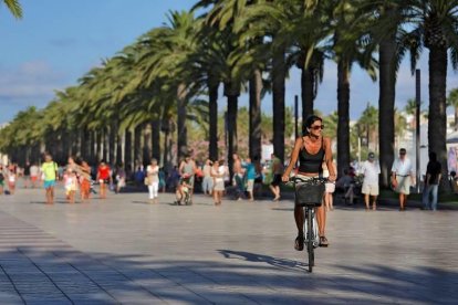 Imagen de una turista en bicicleta por el paseo Jaume I.