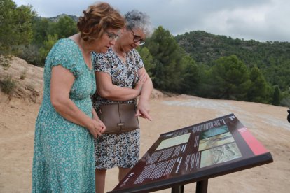 Dos mujeres leen el panel informativo instalado en el Mas de Santa Magdalena, en Móra d'Ebre.