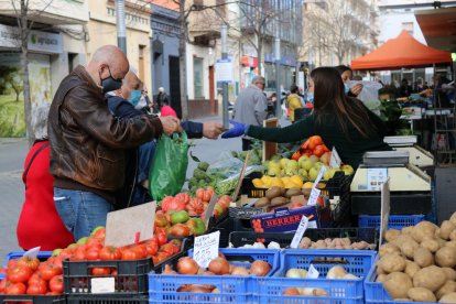 Varias personas comprando las paradas exteriores de un mercado.