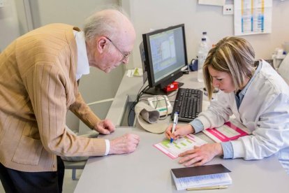 Una enfermera prescribiendo la medicación a un anciano.