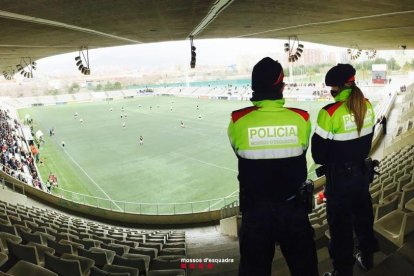 Dos mossos vigilant durant un partit de futbol.