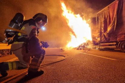 Un bomber extingint el foc del camió.