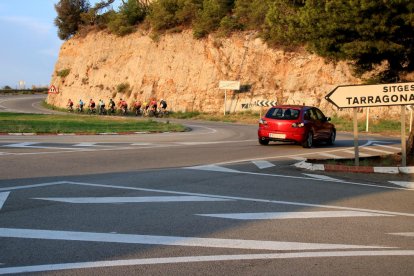 Una desena de ciclistes per la C-31 amb un cotxe darrere seu.