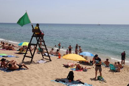 Un socorrista vigila els banyistes que omplen la platja del Pont d'en Botifarreta de Badalona.