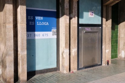 El lateral d'una antiga entitat bancària a Segur de Calafell, actualment tancada i amb un cartell de venda o lloguer.