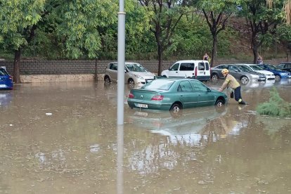 Un bomber ajudant a un dels vehicles que ha quedat afectat per la tromba d'aigua.