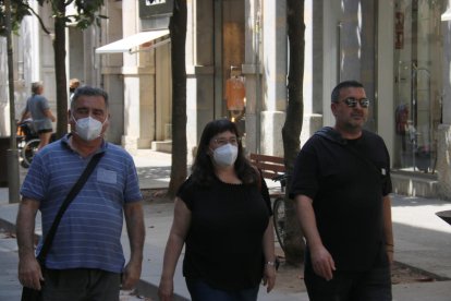 Tres persones caminen pel carrer Santa Clara una d'elles sense mascareta.