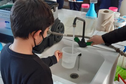 Un niño llena un recipiente de agua en una taller experimental.