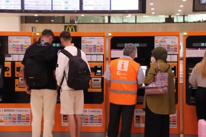 Diverses persones a les màquines d'autovenda de Rodalies de l'estació de Sants.