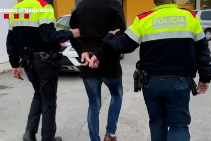 Dos agents dels Mossos d'Esquadra traslladant un dels detinguts.