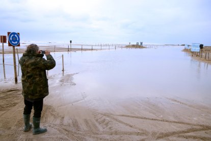 Un hombre toma imágenes del acceso a la barra del Trabucador inundado por el mar.