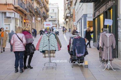 Gent mirant els productes de les paradetes de les botigues del Carrer Sant Agustí.