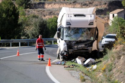 Un operari retira les restes del vehicle que han quedat davant del camió accidentat a Batea.