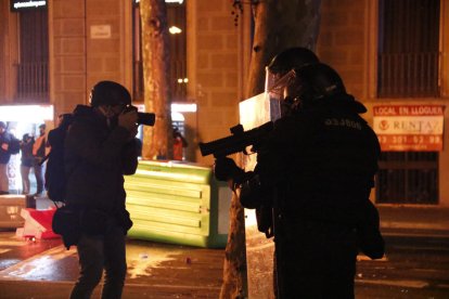 Un periodista fotografía a un agentes de los Mossos con una lanzadera foam.