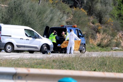 Els agents de la policia i els serveis funeraris aixecant el cadàver de la víctima.