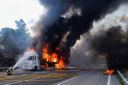 El camió incendiat aquest divendres a l'AP-7 i els Bombers treballant-hi.