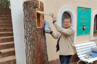 L'alcalde de Cambrils, Oliver Klein, dipositant llibres en un dels arbres habilitats del Parc Samà.