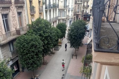 Imagen de dos patinetes circulando por el raval al mediodia.