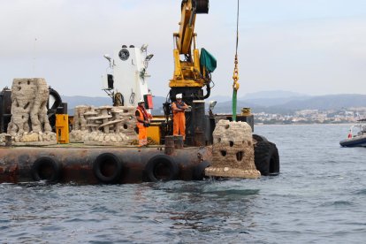 Dos operaris submergint un dels últims biòtops que vorejaran la primera muntanya marina construïda al Port de Torredembarra.