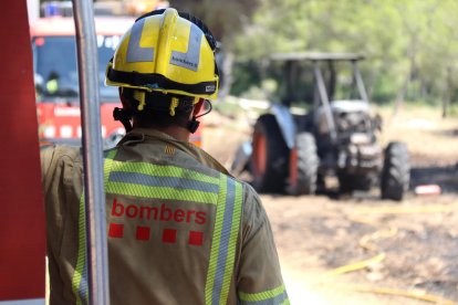 Un bombero mirando el tractor calcinado que ha provocado el incendio en Mont-roig del Camp.