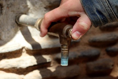 Una persona abriendo el grifo de una fuente de la Espluga de Francolí, de donde no sale agua.