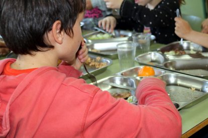 Imagen de archivo de alumnos sentados en una mesa comiendo en el comedor de una escuela.