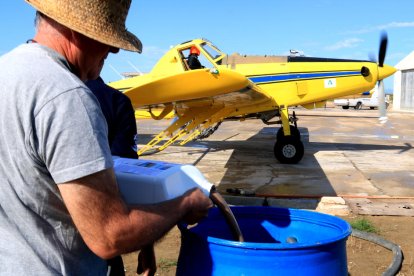 Los técnicos preparen el BTI para cargar el avión que realizan los tratamientos contra los mosquitos en el Delta.