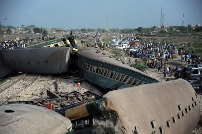 Funcionarios de seguridad y rescate de Pakistán inspeccionan los vagones de un tren que ha descarrilado en el sur de Pakistán, este domingo.