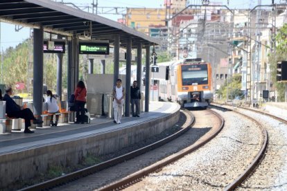 Passatgers esperant a l'andana l'arribada d'un tren a l'estació de Rodalies de Gavà.