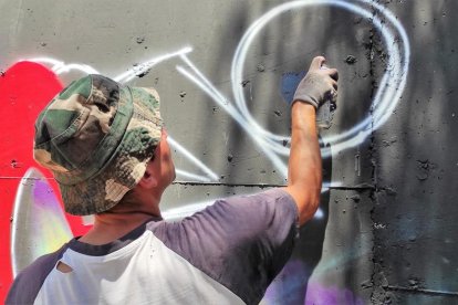 Instant capturat d'un dels artistes pintant un grafiti al mur durant la jornada de dissabte.