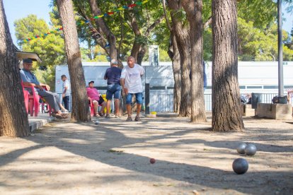 Alguns participants aprofiten per exercitar-se a l'ombra dels arbres, entre les pistes i el local social.