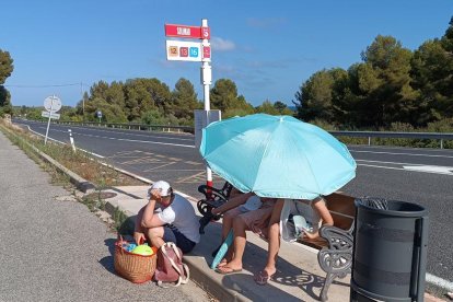 Usuaris de l'EMT esperant l'arribada del bus sota un paraigues.