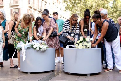 Familiares y víctimas del 17-A depositan claveles a las jardineras de la Rambla.