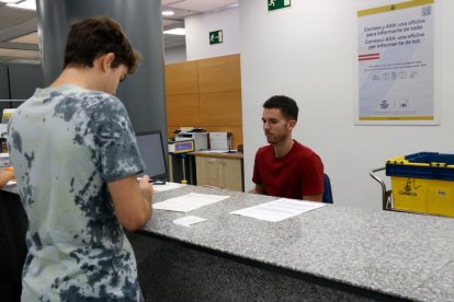 Un treballador de Correus explica el procediment per demanar el vot postal a un ciutadà aquest dissabte.