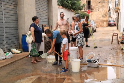 Veïns de Santa Bàrbara l'endemà dels aiguats netejant els baixos inundats pels forts aiguats.