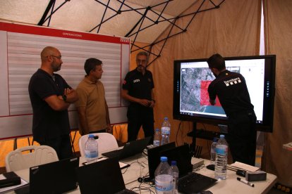 El inspector del cuerpo de Bomberos, Oriol Corbella, mostrando a las autoridades locales la zona afectada por las trombas de agua en el centro de mando.